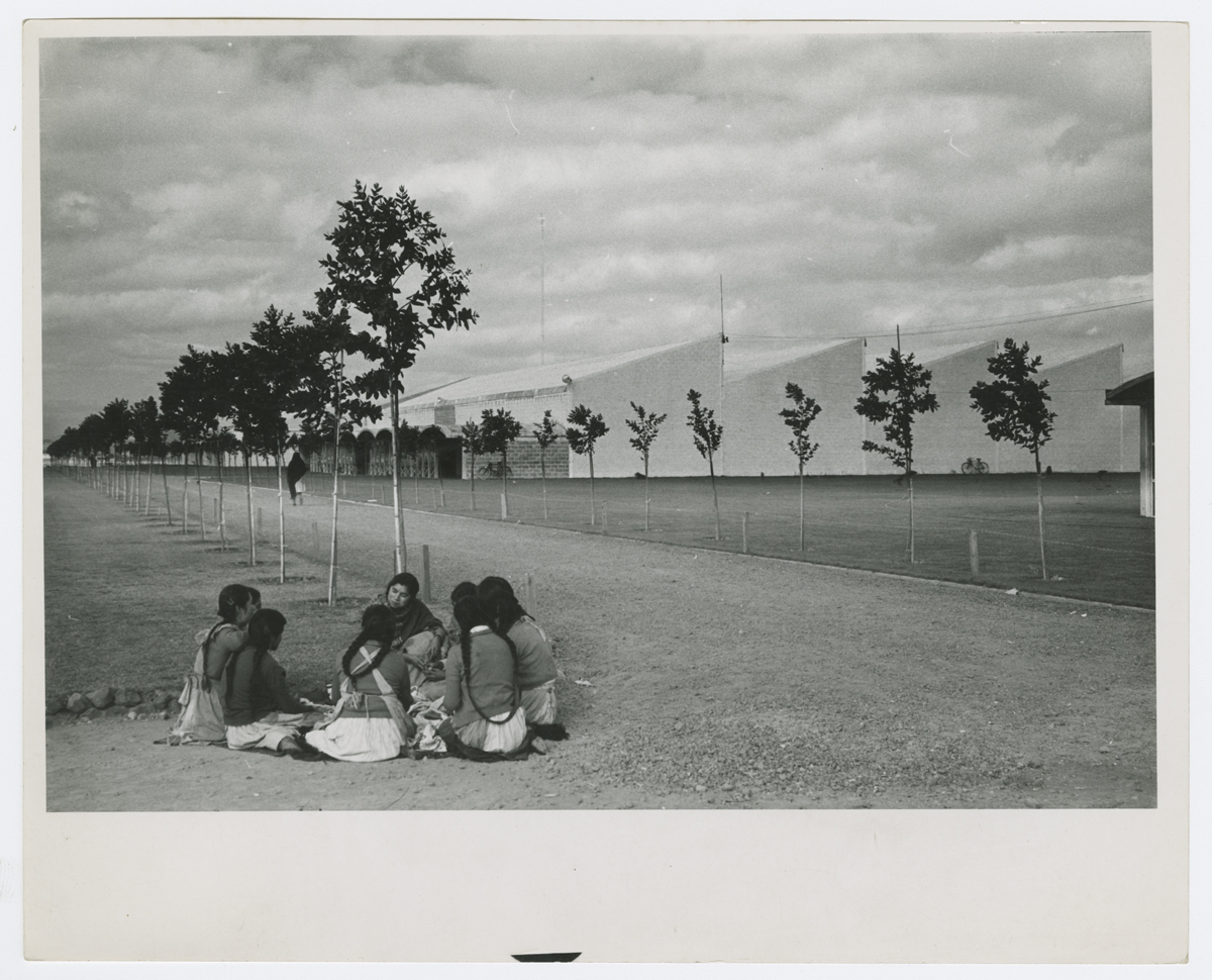 Mujeres trabajadores tomando un descanso, al fondo las naves industriales con dientes de sierra. (AGP 64-400, AAM-FA/UNAM)